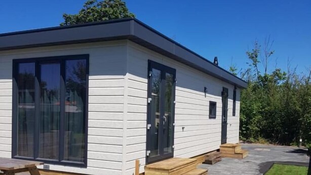 A modern mobile home with large windows, a patio, and a well-maintained lawn. - Chalet 34 (4 persons) (Petten)