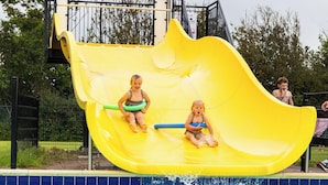 A yellow slide over a pool with two children on it. - Chalet 34 (4 persons) (Petten)