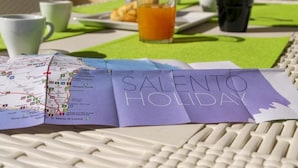 Un mapa con el texto 'SALENTO HOLIDAY', un teclado y una mesa con un mantel verde.
