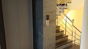 An elevator, a staircase, and a door with a security lock. - Sam's Court Elite Stay (Manachanallur)