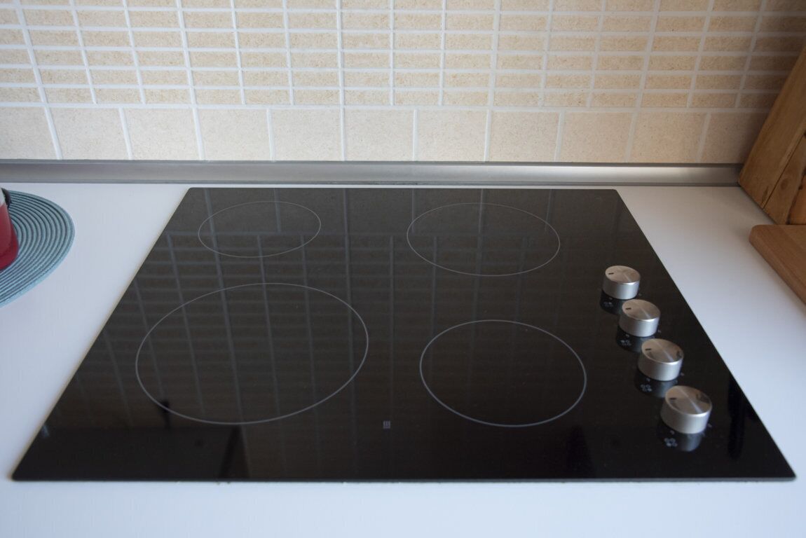 A kitchen with a black induction cooktop and four burners.