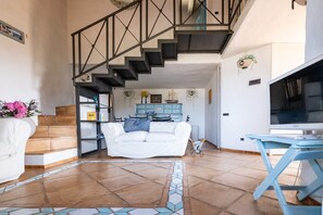 Ein Wohnzimmer mit Treppe, einem weißen Sofa, einem Fernseher und einem blauen Tisch.