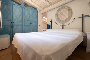 Ein Schlafzimmer mit einem Bett, einem blauen Kleiderschrank, einem runden Spiegel und einem weißen Nachttisch.
