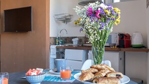 Morgenmadsbord med kager, et glas appelsinjuice og en blomsteropsætning.