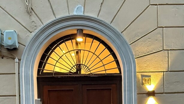 En dobbelt dør af tr æ med en metalders over, en lille lampe til højre og en brostensbelagt forplads foran.