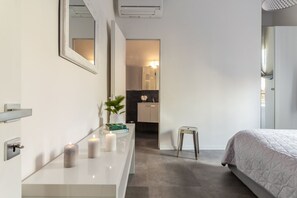 Ein modernes Schlafzimmer mit einem großen Bett, einem Schminktisch mit Spiegel und einem kleinen Hocker.