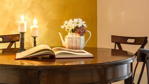 A round wooden table with an open book, two lit candles, and a vase with flowers. - Santonofrio Gold - Two Bedroom Apartment, Sleeps 5 (Rome)