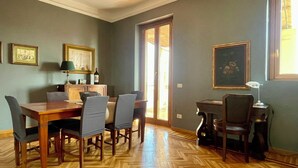 Un comedor con una mesa y sillas de madera, un armario y cuadros en las paredes.