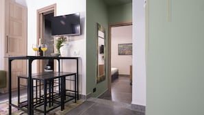 A hallway with a black metal table, a television mounted on the wall, and a painting on the adjacent wall. - Vatican Boutique Apartment St. Peter Dome View (Rome)