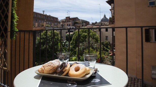 A table with pastries and glasses on a balcony overlooking a cityscape. - Vatican Boutique Apartment St. Peter Dome View (Rome)