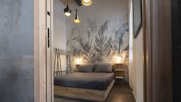A bedroom with a bed, wooden headboard, wall art, and pendant lights. - Vatican Boutique Apartment with Large Terrace (Rome)