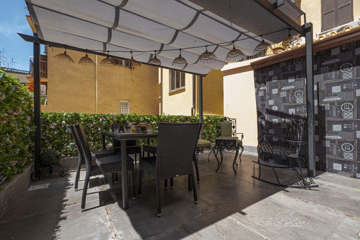 An outdoor patio with a table and chairs, a bench, and a patterned wall.