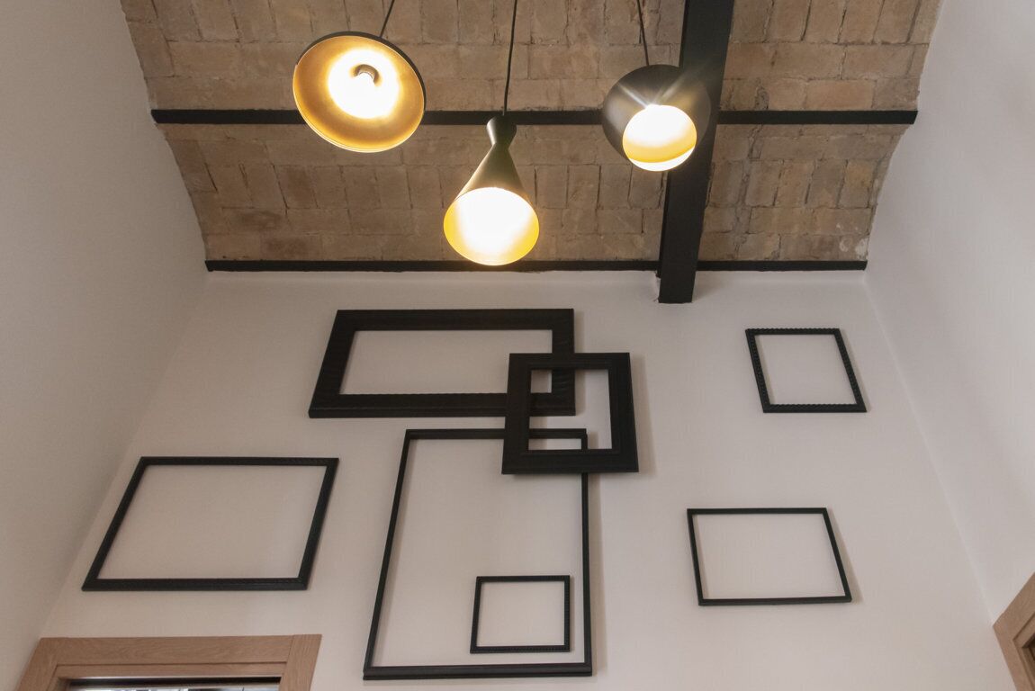 Une pièce avec un plafond en briques, des encadrements de murs noirs et des lampes suspendues.