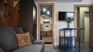 A living room with a grey sofa, a small table, a TV mounted on the wall, and a wooden cabinet. - Vatican Boutique Apartment with Large Terrace (Rome)