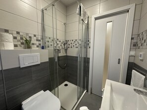 A modern bathroom with a glass-enclosed shower, a toilet, and a sink. - Anděl Work & Chill Studio (Prague)