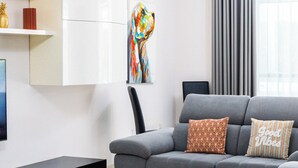 Ein modernes Wohnzimmer mit einem grauen Sofa, einem schwarzen Couchtisch und einem Flachbildfernseher.