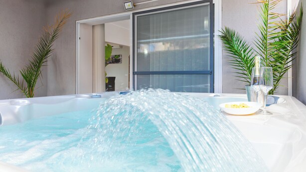 Ein Whirlpool mit Wasserstrahlen, ein Glas Wasser und ein Teller mit Speisen.