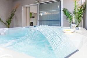A hot tub with water jets, a glass of water, and a plate with food. - Swieqi Jacuzzi (Swieqi)