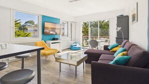 Ein modernes Wohnzimmer mit einer Couch, einem Glastisch, einem gelben Sessel und einem Fernseher.