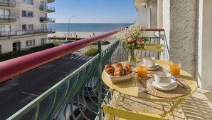 Ein Balkon mit Frühstückstisch, Blick auf eine Straße und den Strand.