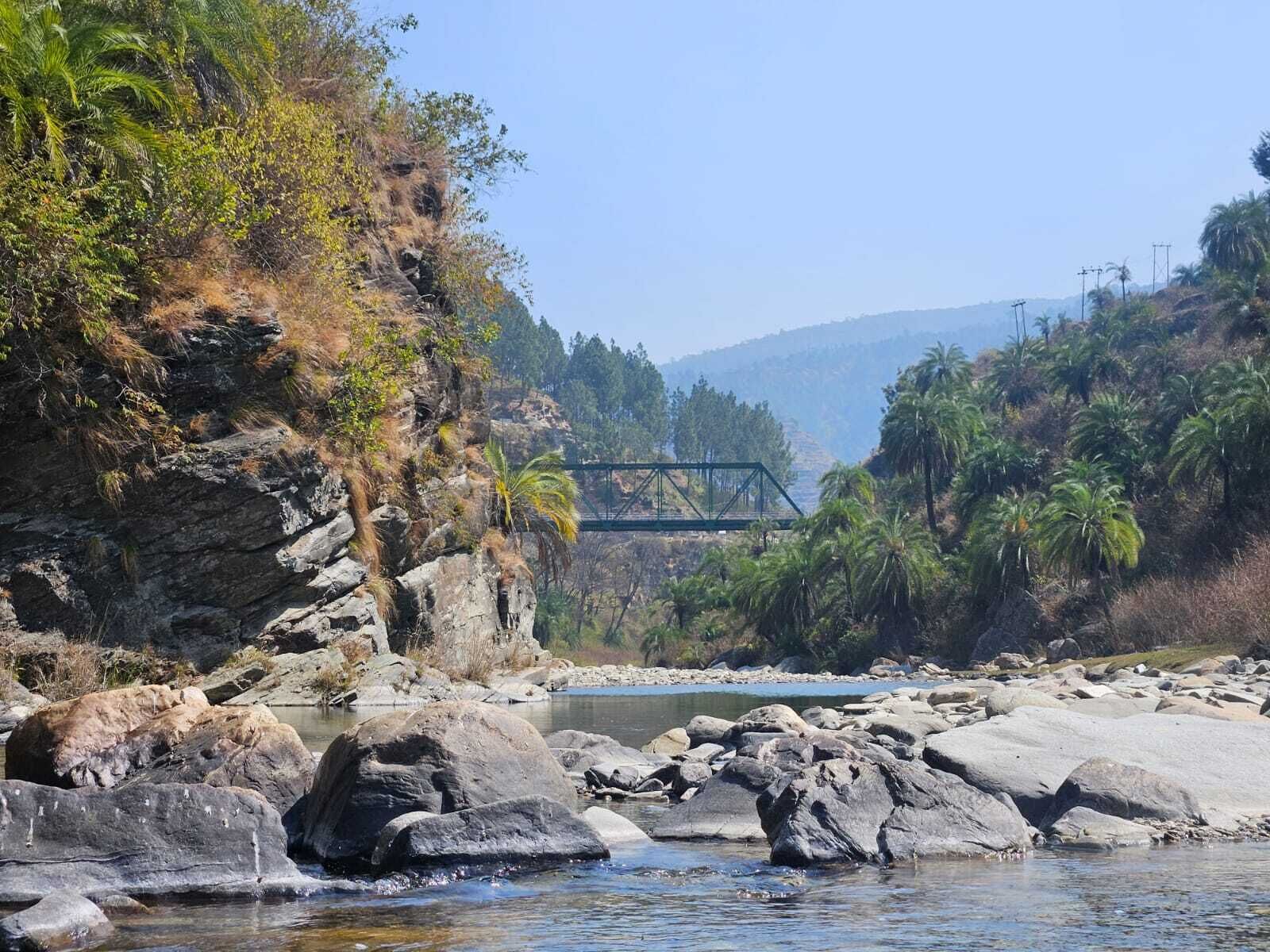 A river with rocks and a bridge in the background.