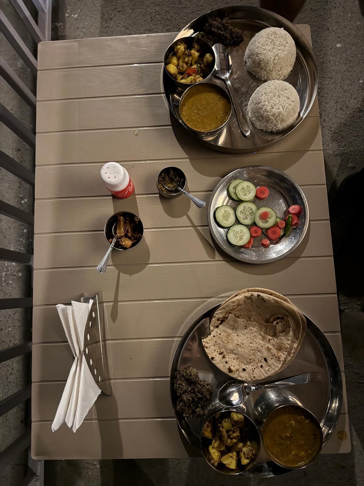 A table with various dishes, including rice, vegetables, and a plate of flatbreads.
