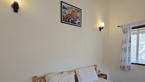 Une chambre à coucher avec un lit, une tête de lit en bois, des lampes fixées au mur, un tableau encadré, une fenêtre avec des rideaux et une table de chevet.