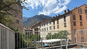 Una terraza con barandillas de metal, una mesa y sillas.