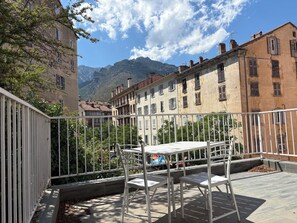 A terrace with metal railings, a table, and chairs. - 2-bed apartment with large terrace (Corte)