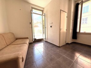 A room with a sofa, a sliding door, and a window with a view of buildings. - 2-bed apartment with large terrace (Corte)