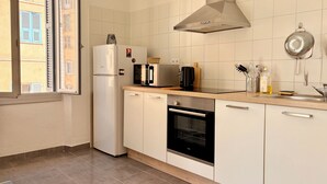 Una cocina moderna con refrigerador, microondas, horno y un ventanal amplio.