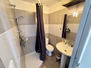 Een douche, handdoeken, zeep, toiletpapier