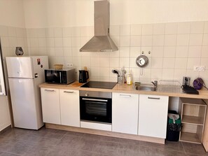 A compact kitchen with a microwave, oven, sink, and a stainless steel range hood. - 2-bed apartment with large terrace (Corte)