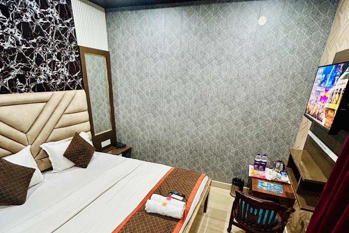 A hotel room with a bed, a desk, a chair, a television, and a ceiling fan.