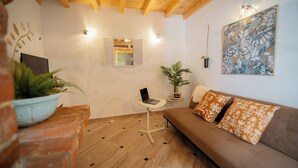 Un saló acollidor amb un sofà, una taula petita amb un ordinador portàtil, una planta en test i una obra d'art penjada a la paret.