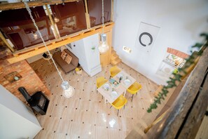 En spiseplads med et bord dækket til fire personer, omgivet af gule stole, en hængende lampe og et træloft.