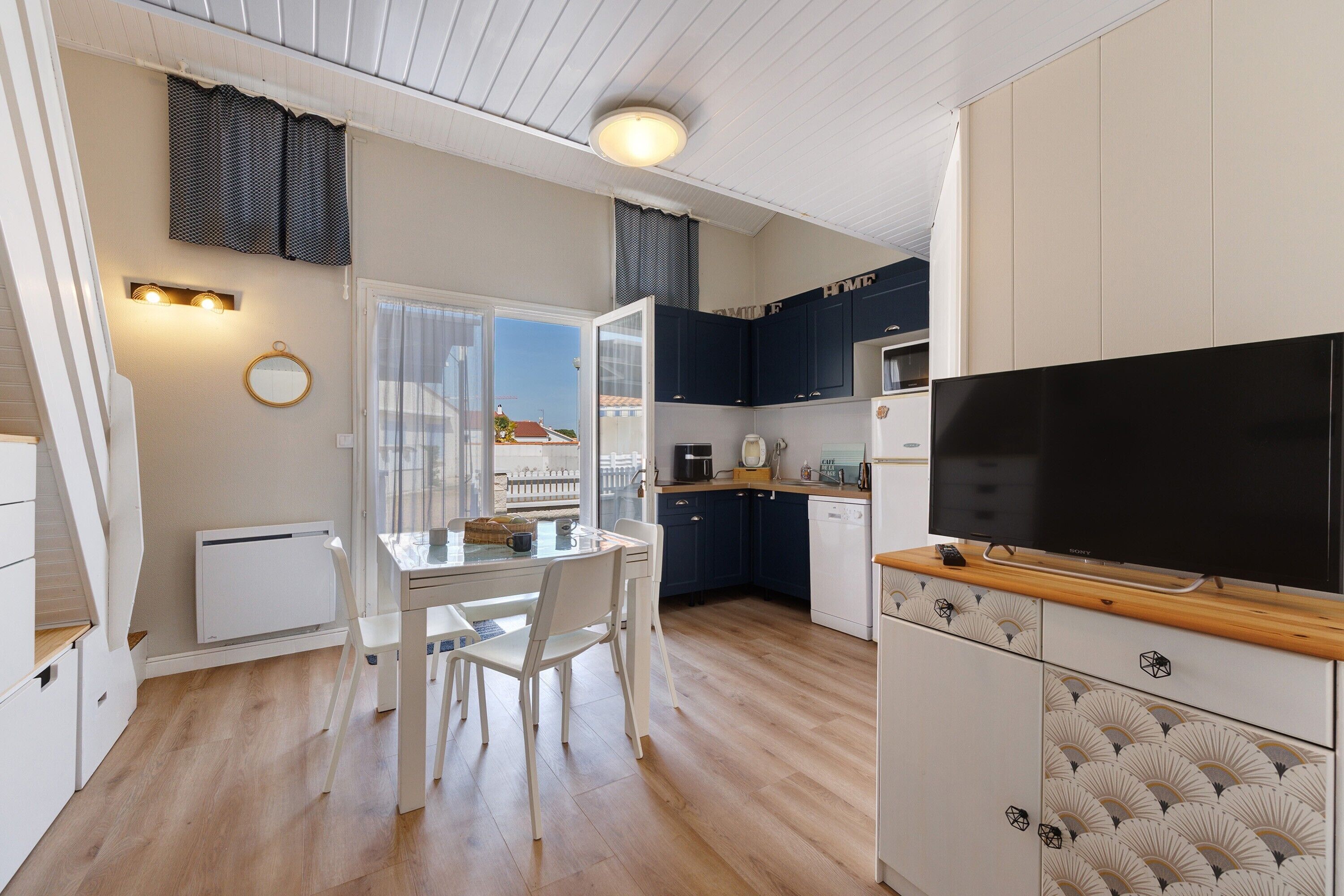 A modern kitchen with white cabinets, a wooden countertop, and a built-in TV.