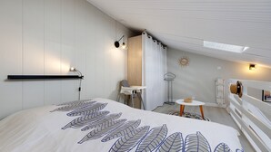 A bedroom with a bed, a chair, a small table, and a radiator. - La Pause Iodée – Close to Beaches and Town Center (La Tranche-sur-Mer)