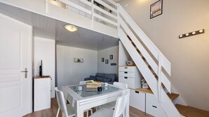 A room with a dining table, chairs, a staircase, and a small seating area. - La Pause Iodée – Close to Beaches and Town Center (La Tranche-sur-Mer)