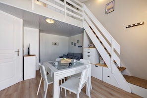 Ein Zimmer mit Esstisch, Stühlen, einer Treppe und einer kleinen Sitzecke.