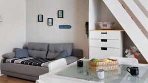 A modern living room with a sofa, a glass coffee table, a white cabinet, and a wicker basket on the table. - La Pause Iodée – Close to Beaches and Town Center (La Tranche-sur-Mer)