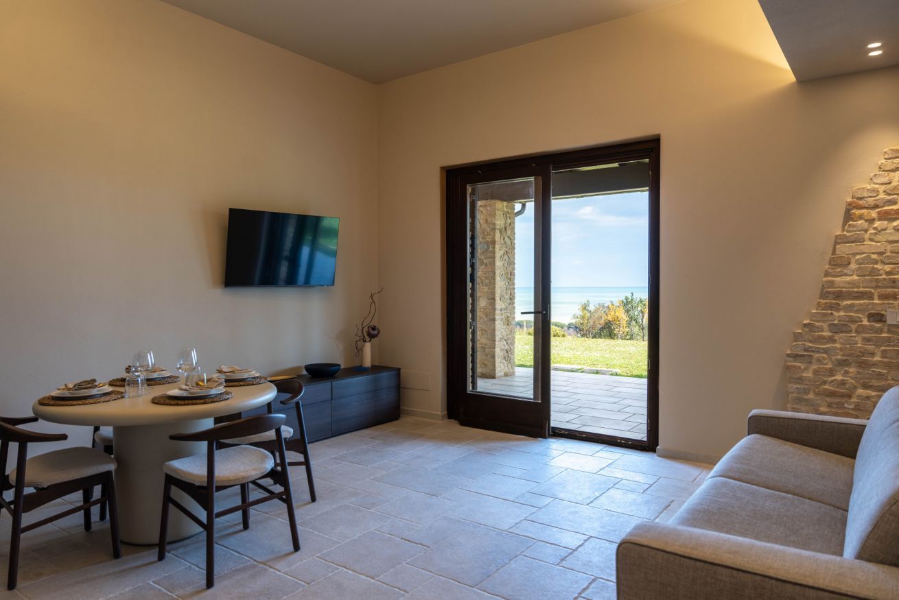 A dining area with a table set for four, a sofa, and a view of the outdoors.