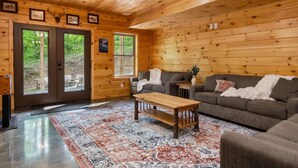 A wooden interior with a sofa, coffee table, and a rug. - Fernwood Lodge - 15 Min To Raystown Lake (Huntingdon)