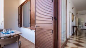A room with a wooden door, a window, a table with chairs, and a tiled floor.