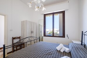 Une chambre à coucher comprenant un lit, une chaise, une armoire, une fenêtre et un luminaire au plafond.