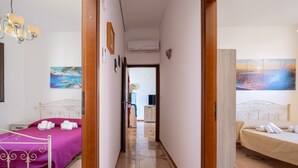 A hotel room with a bed, a bathroom, and a hallway leading to another room.