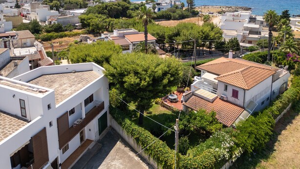 A residential area with houses, a clear view of the sea, and a street with greenery.