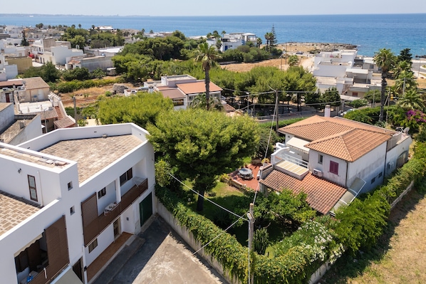 Zona residencial con casas, vista despejada al mar y una calle con vegetación.