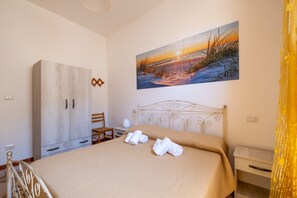 A bedroom with a bed, a wardrobe, a painting, and a chair. - Holiday Home 'Vacanza Alle 4 Colonne - 1' with Balcony, Wi-Fi and Air Conditioning (Santa Maria al Bagno)