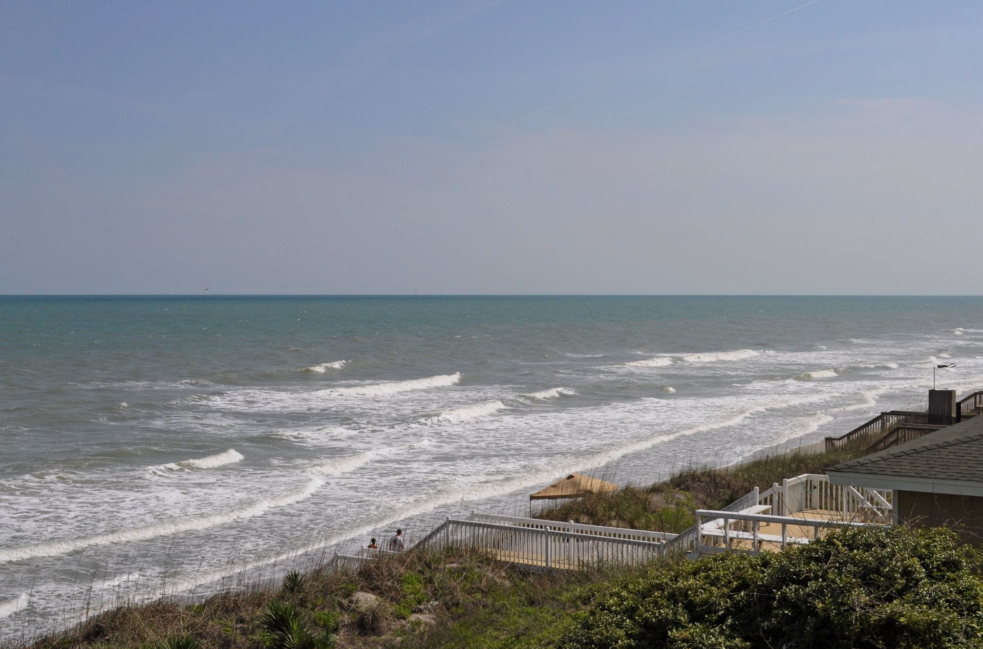 Une vue sur la côte avec une promenade en bois menant à une plage.